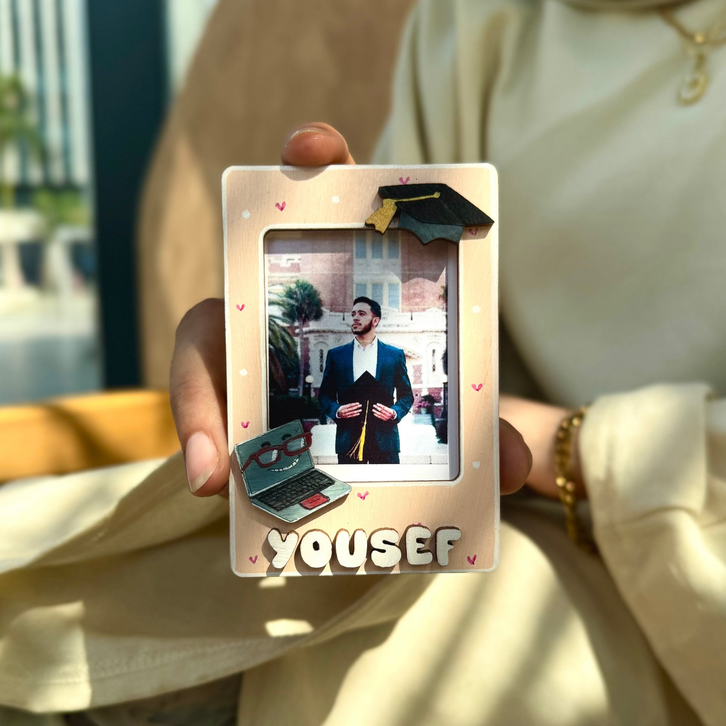 Person holding a photo album with a picture of a man and the name 'Yousef' on it.