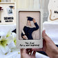 A person holds a square cream-colored keepsake photo frame featuring a 3D paper-cut illustration of a graduation scene with the text 'The End. For a new beginning'.