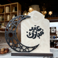 Decorative stone with Arabic calligraphy and a black crescent moon on a patterned surface.