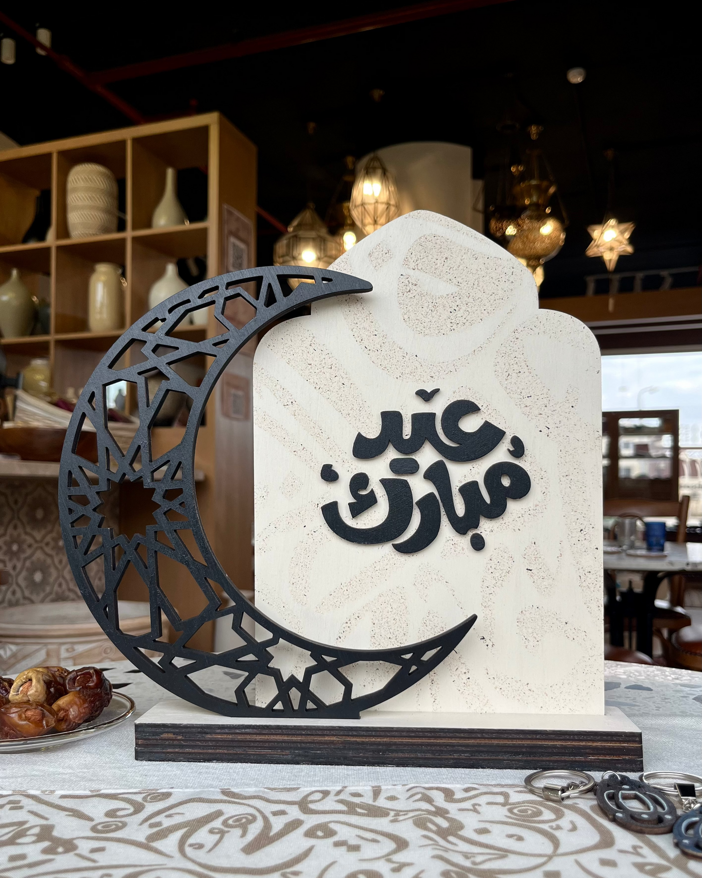 Decorative stone with Arabic calligraphy and a black crescent moon on a patterned surface.